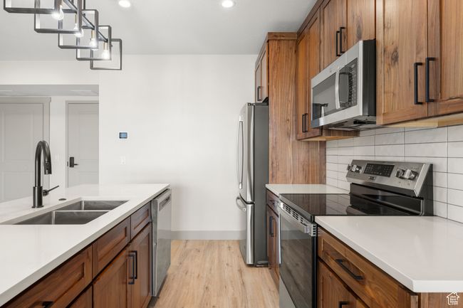 Kitchen featuring stainless steel appliances, a sink, light wood-style floors, brown cabinets, and recessed lighting | Image 7
