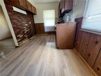 Kitchen with backsplash, light hardwood / wood-style floors, and wooden walls | Image 2