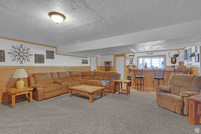 Carpeted living room featuring a textured ceiling, wood walls, and wainscoting | Image 23