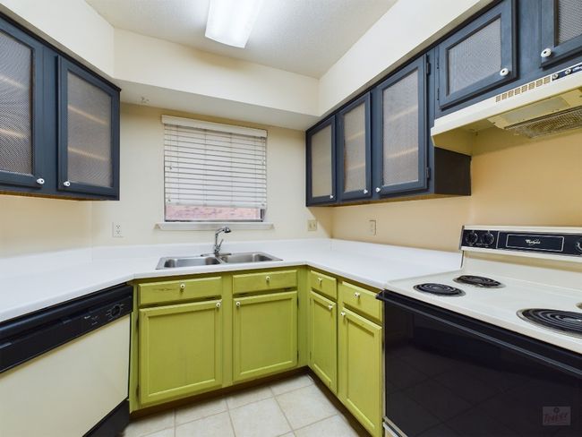 Kitchen with a sink, light countertops, under cabinet range hood, electric range, and dishwasher | Image 11