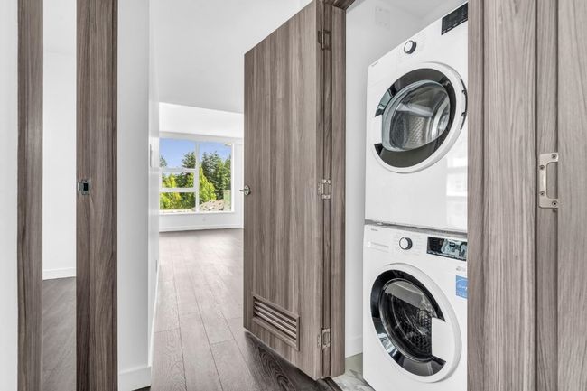 Laundry area featuring stacked washer and clothes dryer and dark wood-style flooring | Image 13