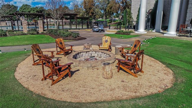 Relax and unwind in this beautifully designed outdoor gathering space, featuring a custom stone fire pit surrounded by rustic wooden chairs. Nestled within the Sugar Creek community, this inviting amenity offers a perfect setting for evening conversations and social gatherings. Just steps away, enjoy the lush landscaping, pergola-covered seating areas, and a sparkling pool. Experience the charm and tranquility of Sugar Creek living! | Image 43