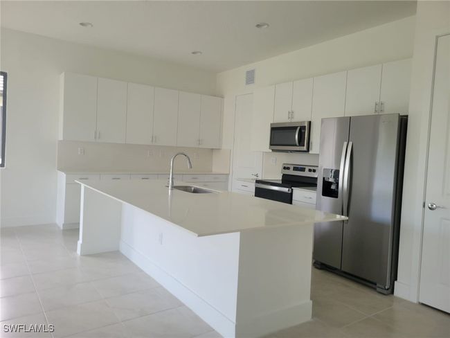 Kitchen with stainless steel appliances, a sink, white cabinets, light countertops, and recessed lighting | Image 4