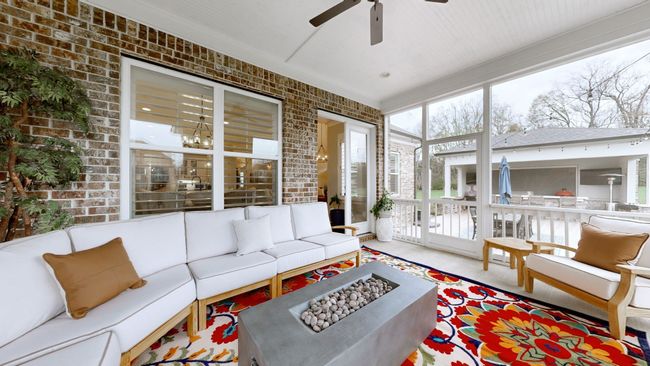 Screened-in porch offers the perfect blend of comfort & style—featuring a brick fireplace, ample seating, & views of the outdoor kitchen, making it an ideal space for relaxing, hosting, & enjoying the outdoors year-round. | Image 38