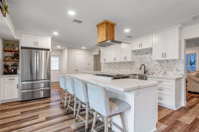 This kitchen is a chef's dream with sleek white cabinets, an extra-large kitchen island perfect for meal prep or entertaining, and stainless steel appliances for ultimate convenience and style. | Image 4