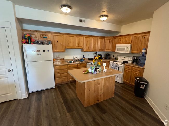 Kitchen featuring visible vents, a sink, dark wood-style flooring, and white appliances | Image 5