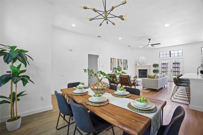 Dining space featuring wood finished floors, a brick fireplace, recessed lighting, a ceiling fan, and a chandelier | Image 5