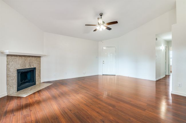 Welcome to your new home! It's everything your family needs. This living room featuring a ceiling fan, a tile fireplace, wood finished floors, and vaulted ceiling. | Image 4