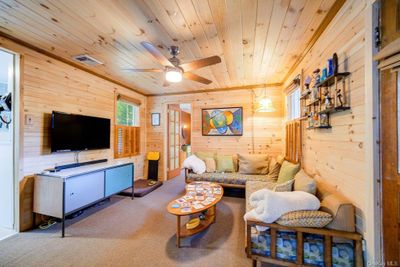 Living room with wooden ceiling, wooden walls, ceiling fan, and carpet flooring | Image 3