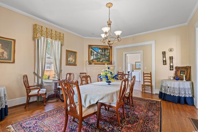 Dining room featuring a chandelier, wood finished floors, crown molding, and washing machine and clothes dryer | Image 4