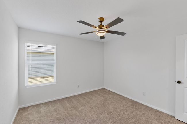 Empty room featuring light colored carpet, baseboards, and a ceiling fan | Image 29