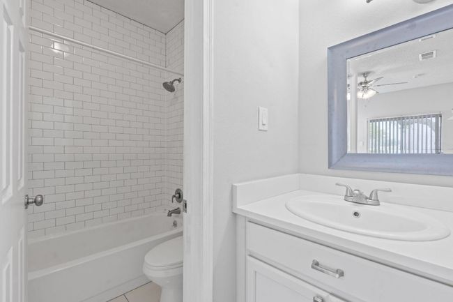 Bathroom featuring toilet, shower / washtub combination, vanity, tile patterned floors, and ceiling fan | Image 18