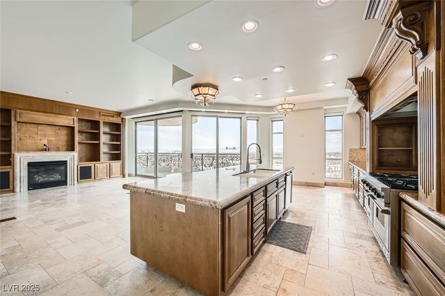 Kitchen with stone tile floors, a sink, recessed lighting, double oven range, and light stone countertops | Image 14
