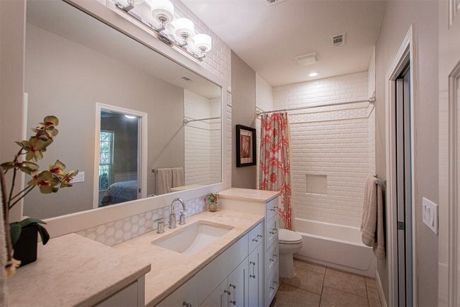 Ensuite bathroom featuring tile patterned floors, vanity, shower / bath combination with curtain, and toilet | Image 23