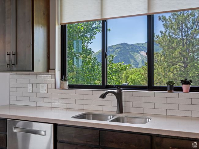 Kitchen featuring a sink, dishwasher, light countertops, tasteful backsplash, and dark brown cabinetry | Image 20