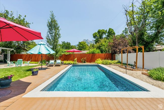 View of swimming pool featuring a wooden deck, a fenced backyard, and a patio area | Image 46