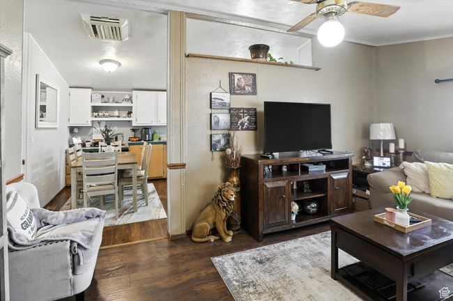 Living room with dark wood-type flooring, ceiling fan, and crown molding | Image 5