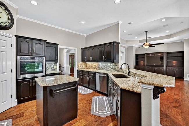 Kitchen with stainless steel appliances, a sink, a peninsula, a ceiling fan, and ornamental molding | Image 17