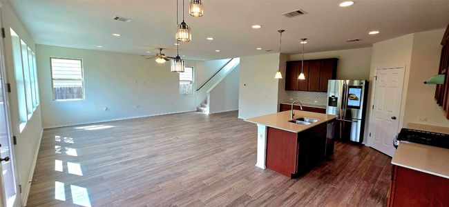 Kitchen featuring stainless steel fridge, light countertops, open floor plan, tasteful backsplash, and a kitchen island with sink | Image 11