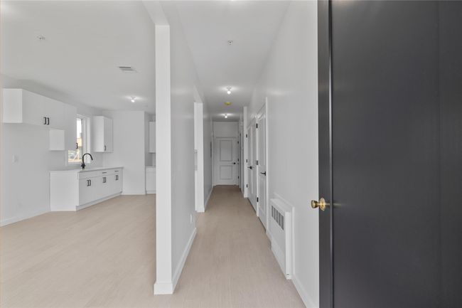 Corridor featuring light wood-style flooring, visible vents, baseboards, and a sink | Image 40