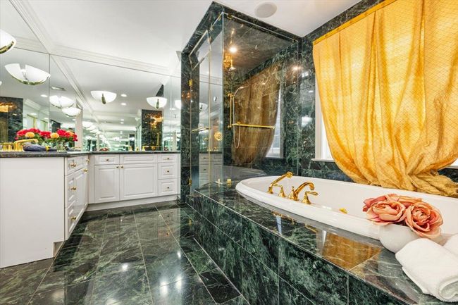 Bathroom with marble tiled floors, a tile shower, a bath, vanity, and ornamental molding | Image 17