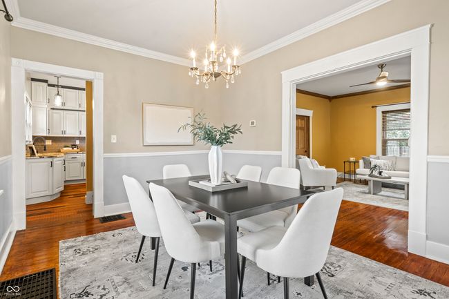 dining space with ornamental molding, dark wood-style floors, ceiling fan, and a chandelier | Image 16