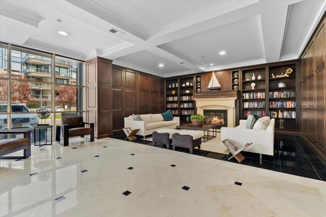 Living room with crown molding, a glass covered fireplace, built in shelves, visible vents, and coffered ceiling | Image 24