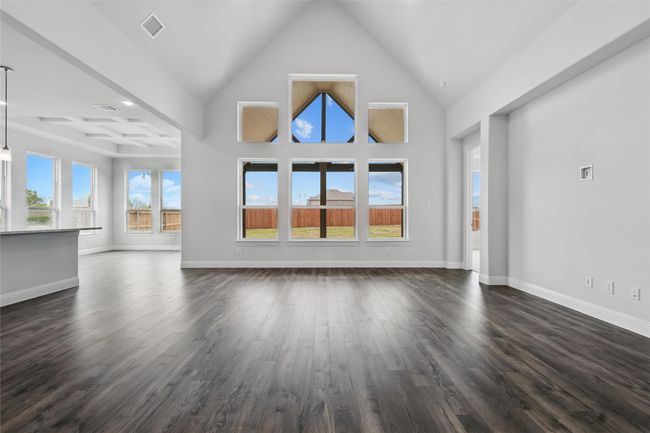 Unfurnished living room featuring dark wood-style flooring, high vaulted ceiling, baseboards, and visible vents | Image 13
