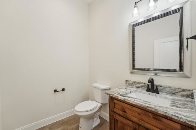 Half bath featuring baseboards, toilet, wood plank tile floor, and vanity | Image 25