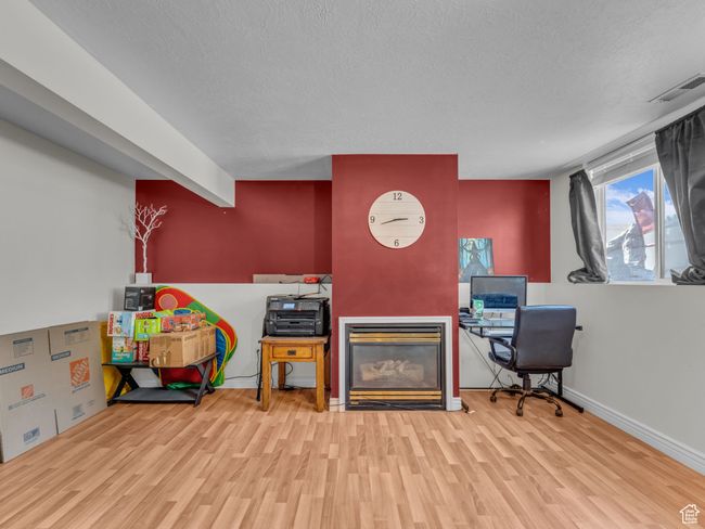 Office space with wood finished floors, a textured ceiling, a glass covered fireplace, and baseboards | Image 17
