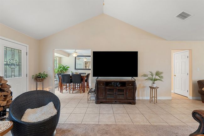 Living room featuring light tile patterned floors, vaulted ceiling, a ceiling fan, and baseboards | Image 15