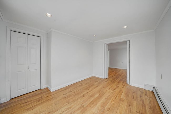 Unfurnished bedroom featuring light hardwood / wood-style flooring, a closet, crown molding, and a baseboard heating unit | Image 31