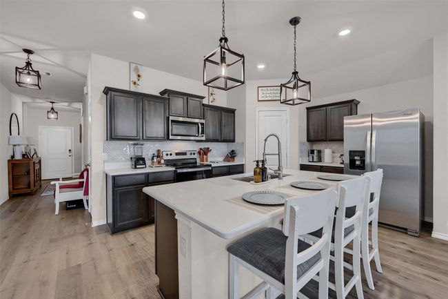 Kitchen with stainless steel appliances, light wood finished floors, tasteful backsplash, light countertops, and recessed lighting | Image 12