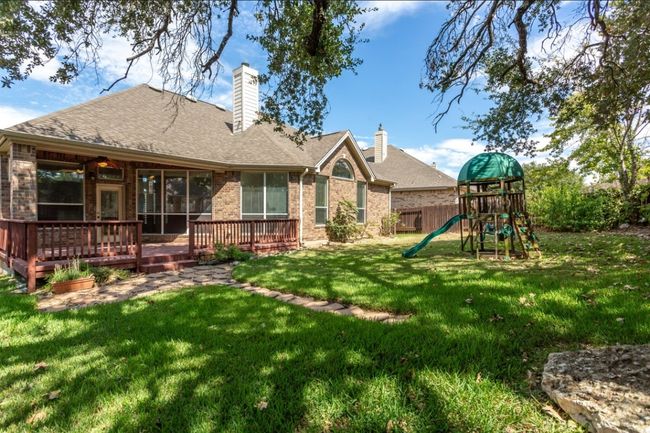 Back of house featuring a playground, a lawn, a chimney, fence, and brick siding | Image 28