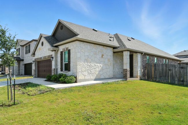 View of home's exterior with a shingled roof, stone siding, and concrete driveway | Image 4