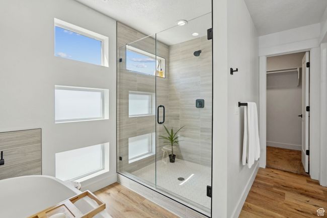 Full bathroom with a spacious closet, a healthy amount of sunlight, a soaking tub, and a stall shower | Image 19