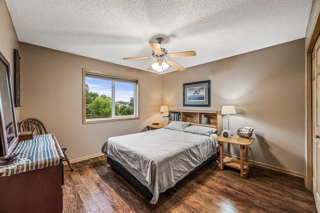 The main floor bedroom is spacious with neutral colors, gleaming hard surface floors, abundant natural light and a ceiling fan for added comfort. | Image 16