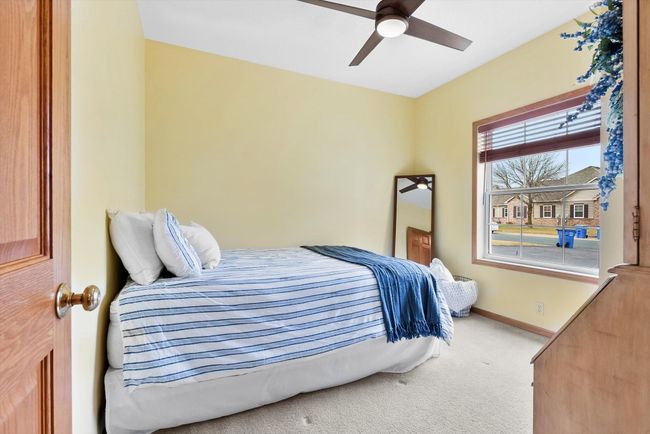 Spacious second bedroom with a large window for natural light and a modern, updated ceiling fan. | Image 21