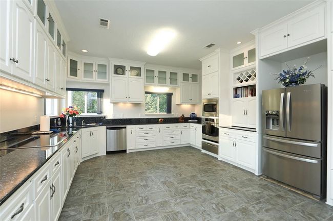 Kitchen features microwave/convection combo, convection oven, and warming drawer. Appliance garage, pull out drawers in cabinets, pull out spice storage, and cushion floor that looks like slate tile complete this huge kitchen. | Image 20