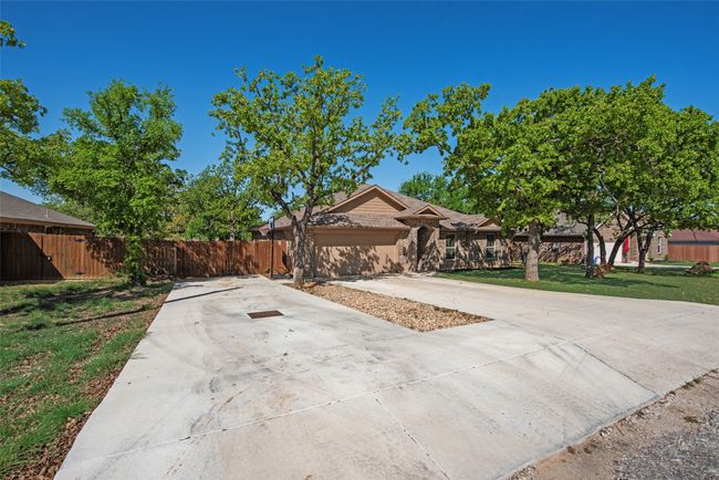 View of front of house featuring concrete driveway, fence, and a front lawn | Image 6