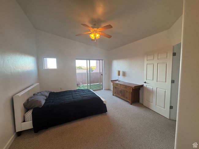 Bedroom featuring light colored carpet, vaulted ceiling, access to exterior, and ceiling fan | Image 4