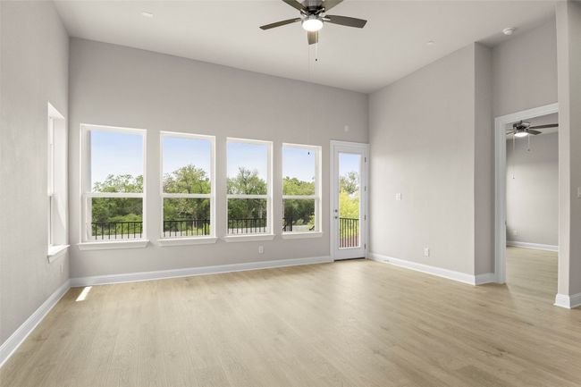 Spare room with ceiling fan, light wood-style flooring, baseboards, and a high ceiling | Image 9