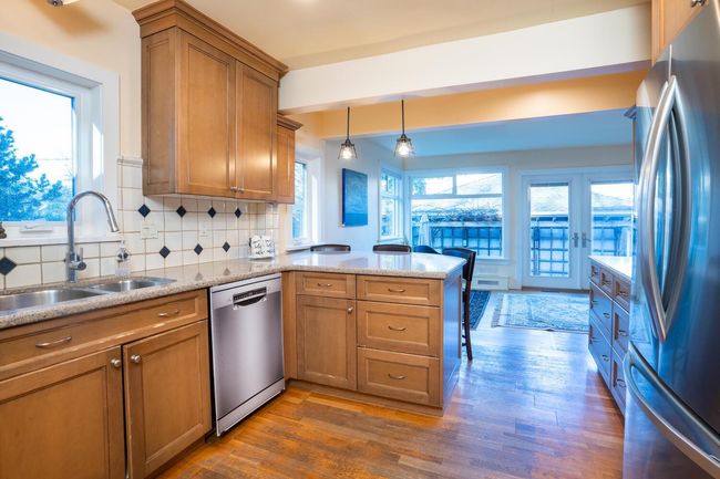 Kitchen featuring a peninsula, a sink, brown cabinetry, backsplash, and appliances with stainless steel finishes | Image 9