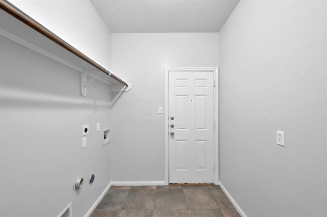 Laundry room, with access to the garage and an expansive shelf with a hanging rod. | Image 32