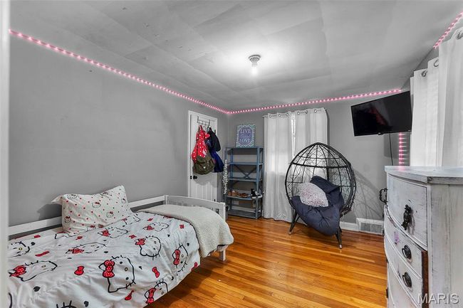 Bedroom with wood finished floors, visible vents, and baseboards | Image 13