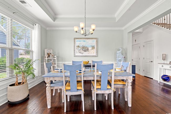 Dining room featuring a tray ceiling, a chandelier, wood-type flooring, and ornamental molding | Image 9