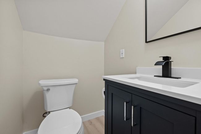 Half bathroom with baseboards, toilet, wood finished floors, vanity, and lofted ceiling | Image 19