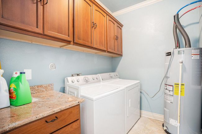 The laundry room is equipped with counterspace and storage space to keep laundry supplies organized and easily accessible. | Image 14