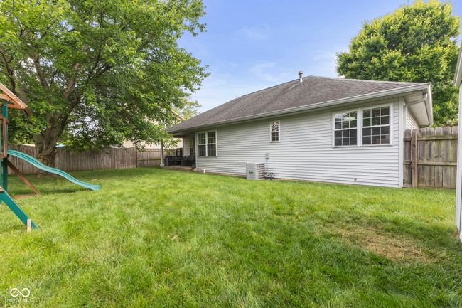 back of house featuring a fenced backyard, a shingled roof, and a playground | Image 37