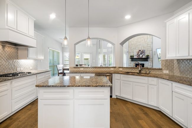 Kitchen with backsplash, recessed lighting, dark wood-type flooring, dark stone countertops, and white cabinetry | Image 14